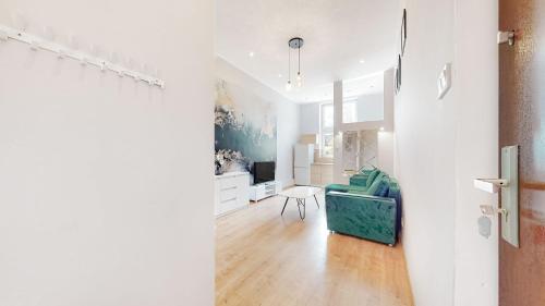 un soggiorno bianco con una sedia blu in una stanza di ZIELONY ZAKĄTEK Apartament w centrum przy Agorze a Bytom