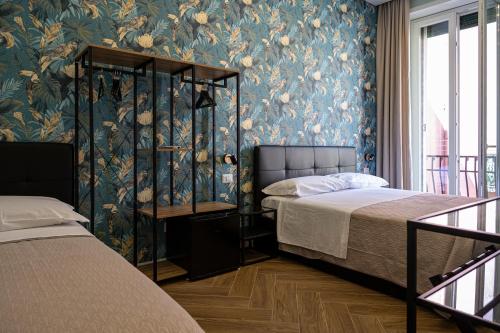 una camera con due letti e una parete con carta da parati floreale di Gravina8 - Rooms in Naples a Napoli