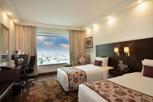 a hotel room with two beds and a large window at Four Points by Sheraton Jaipur, City Square in Jaipur