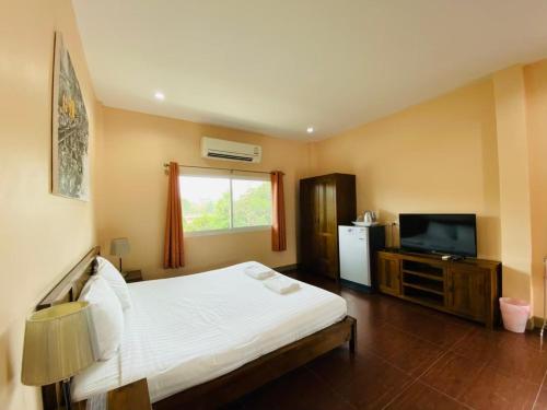 a bedroom with a white bed and a television at Baan Suan Khun Yaiy in Ban Wang Takhrai