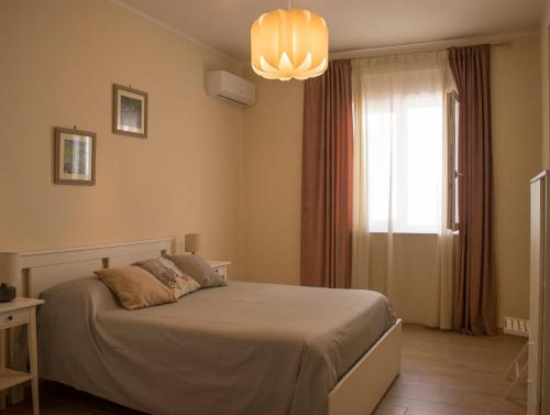 1 dormitorio con cama, ventana y lámpara de araña en Appartamento via Roma, en Recale