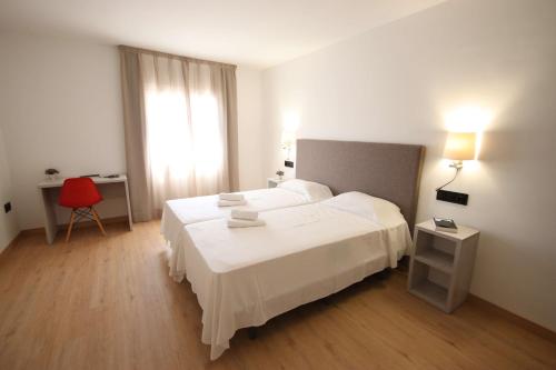 a bedroom with a white bed and a red chair at Hotel Costa Brava in Roses