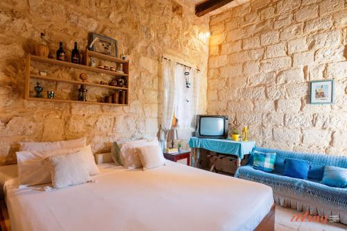 1 dormitorio con cama, sofá y TV en Matli Farmhouse, your stunning Gozo getaway., en Munxar