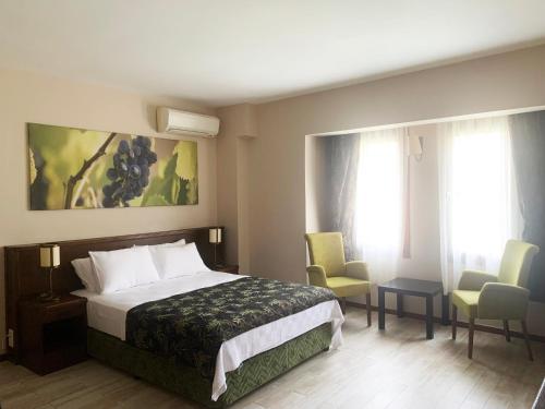 a hotel room with a bed and two chairs at Mitos Hotel in Bozcaada
