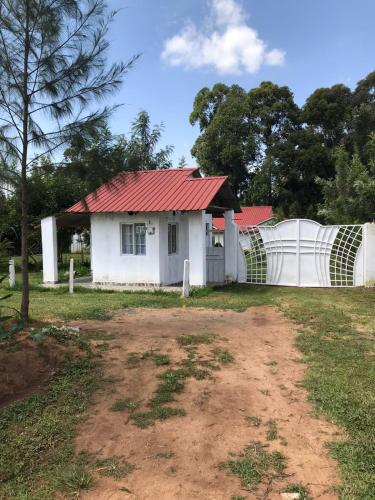 ein weißes Haus mit rotem Dach und einem Zaun in der Unterkunft Ludali homes in Kakamega
