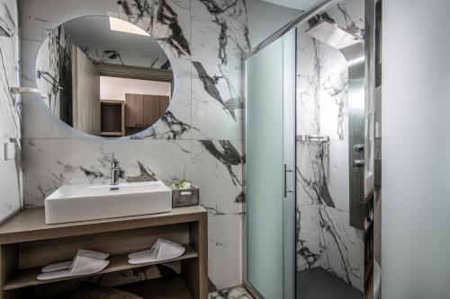 uma casa de banho com um lavatório e um espelho em Crete Resort Sea Side Suites "Adults Only" by Checkin em Gouves