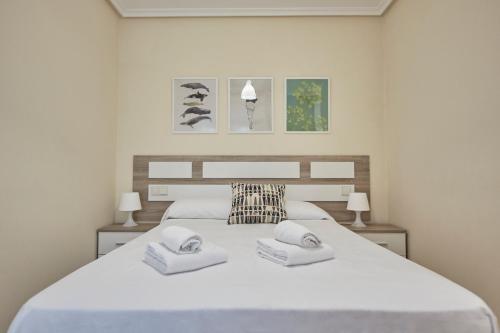 1 dormitorio con 1 cama blanca grande y 2 toallas en Apartagal-Océano V Barreiros, en Barreiros