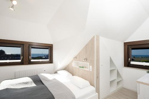 a white bedroom with a bed and two windows at Haus Humml in Grömitz