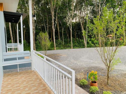 a porch of a house with a white railing at Suanvadee Resort สวนวดี รีสอร์ท in Don Sak