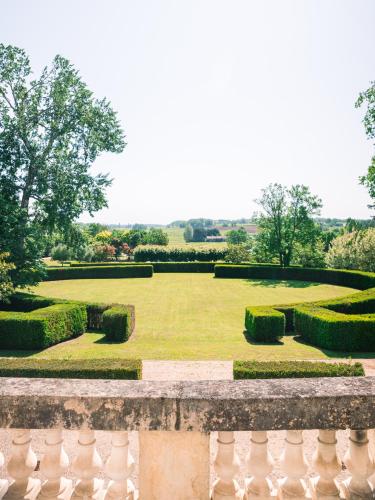 une grande pelouse avec des haies et une clôture dans l'établissement Château de Lussac, à Lussac