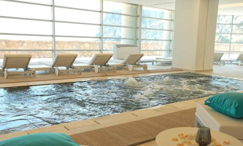 a swimming pool in a room with chairs and a large window at Mercure Quemado Al-Hoceima Resort in Al Hoceïma
