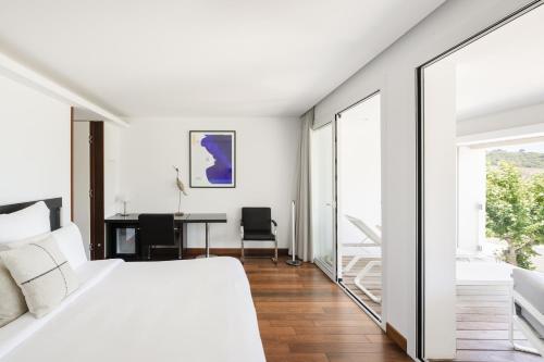 a bedroom with a large white bed and a desk at Les Elmes - H&ocirc;tel, Spa & Plage Priv&eacute;e in Banyuls-sur-Mer