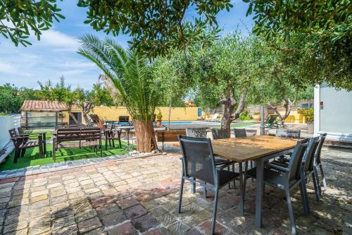 a patio with a wooden table and chairs and trees at Hauzify I Villa del Castell in Altafulla