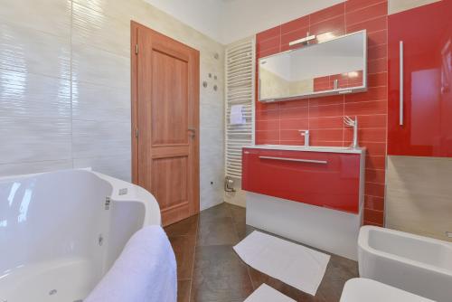 een badkamer met een wit bad en een rode tegelwand bij Apartment Marija Bibinje Zadar in Bibinje