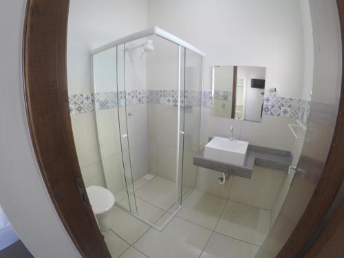 uma casa de banho com um chuveiro, um WC e um lavatório. em Quartos Delfim Moreira em Varginha