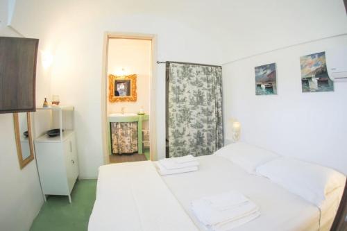 a white bedroom with two beds and a mirror at iFlat Dammusi Thienzo in Pantelleria