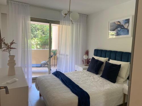 - une chambre avec un lit doté d'une tête de lit bleue et d'une fenêtre dans l'établissement Elegant apartment close to Croisette and Palais de Festival with garage, à Cannes