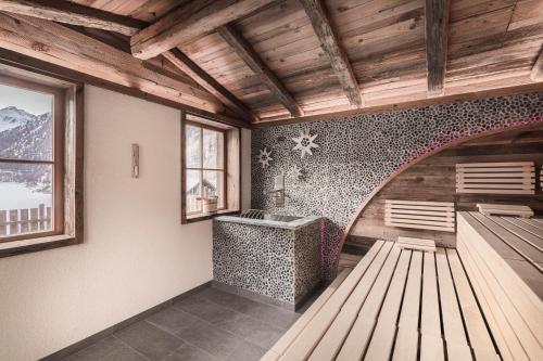 a room with a tub and a sink and a window at Hotel & Chalets Edelweiss in Madonna