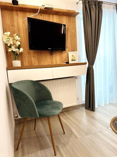 a living room with a tv and a green chair at Apartamente Victory Luxury Eforie Nord in Eforie Nord