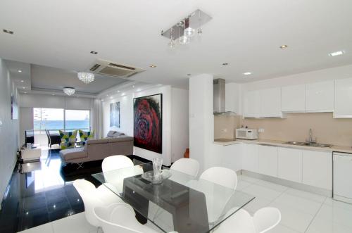 a kitchen and living room with a glass table and white chairs at Gulf Palace Apartments in Limassol