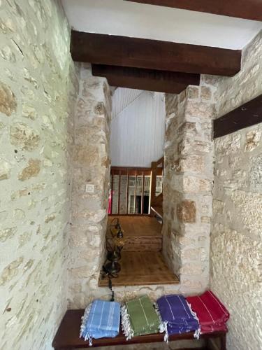 a room with a stone wall with colorful pillows at Domaine du Bonheur en Pierre avec Piscine, Proche Sarlat in Carlux