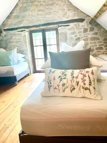 a bed with pillows on it in a room with a stone wall at Domaine du Bonheur en Pierre avec Piscine, Proche Sarlat in Carlux