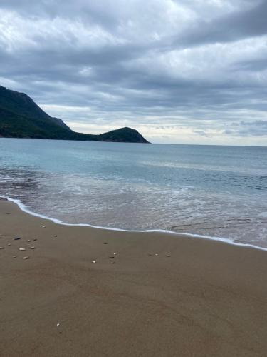 a sandy beach with the ocean and mountains in the background at Karaöz Sapphire Bungalows in Kumluca