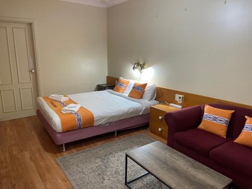 une chambre d'hôtel avec un lit et un canapé dans l'établissement Philadelphia Motor Inn, à Echuca