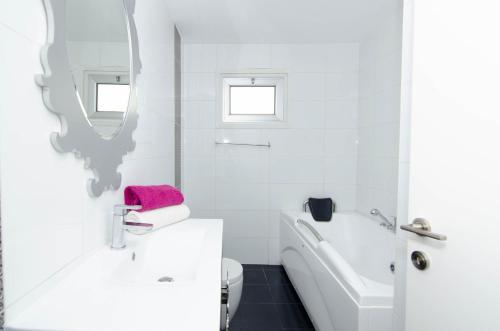 a white bathroom with a white tub and a sink at Gulf Palace Apartments in Limassol
