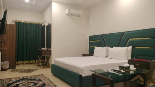 a bedroom with a large bed with a green headboard at Royalton Inn Hotel in Lahore