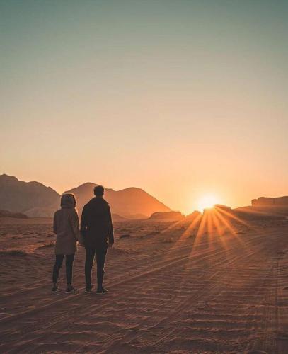 a man and woman standing in the desert watching the sunset at Wadi Rum Nights in Wadi Rum