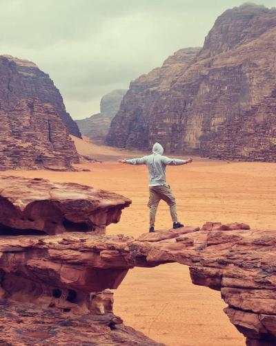 a man standing on a rock in the desert at Wadi Rum Nights in Wadi Rum