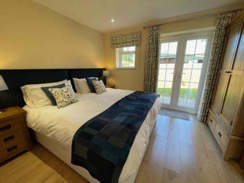 a bedroom with a large bed and a large window at The Haystack Lodge in Tarporley