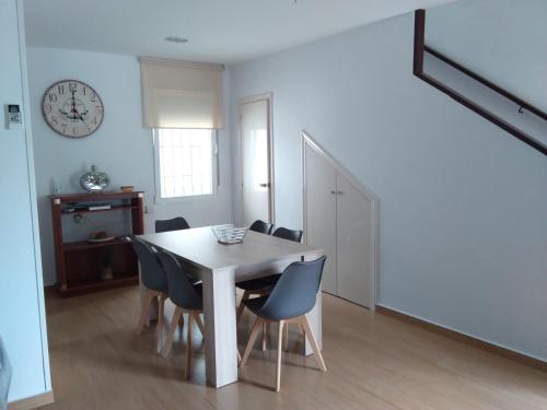 a dining room table with chairs and a clock on the wall at Apartamento Lepanto Playa in Les Cases d'Alcanar