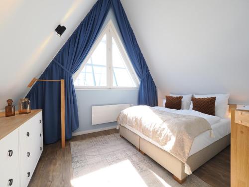 a bedroom with a bed with blue curtains and a window at Seebrücke Heringsdorf - Appartement mit 1 Schlafzimmer und Balkon S7 in Heringsdorf