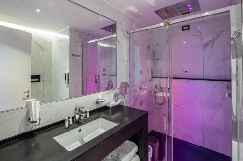 un bagno rosa con lavandino e doccia di Hotel Monaco a Lignano Sabbiadoro