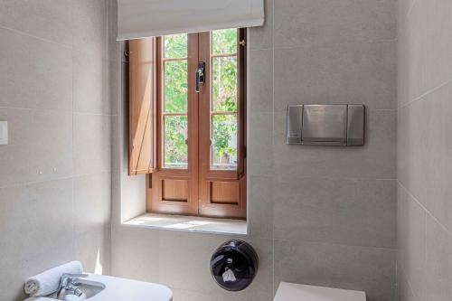 baño con espejo, lavabo y ventana en Apartamentos Recaredo 7 en Sevilla
