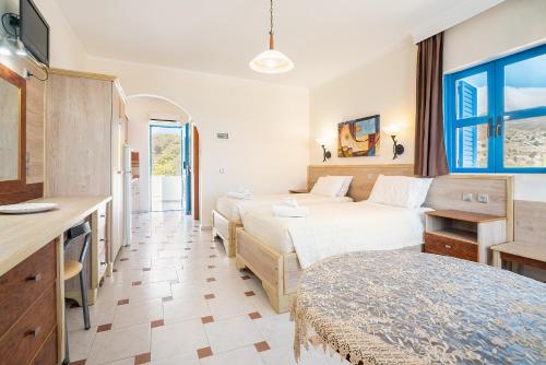 LivadiaにあるLivadia Beach Tilos Apartmentのベッド2台とデスクが備わるホテルルームです。