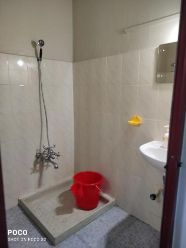 a bathroom with a bucket on the floor and a sink at Redrose Service Apartment in Kannur