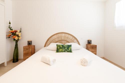 - une chambre avec un grand lit blanc et un vase de fleurs dans l'établissement Viviane - T3 reposant - Jardin - Garage - Wifi, à Vannes
