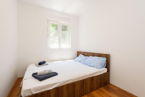 a small bedroom with a bed with white sheets and blue pillows at Peninsula Apartment in Žuljana