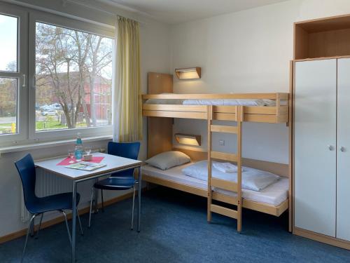 a room with bunk beds and a table and a desk at Jugendherberge Wolfsburg in Wolfsburg