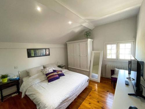 a bedroom with a white bed and a television at Belle maison familiale Basque in Bayonne