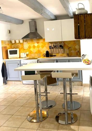 une cuisine avec un comptoir et des tabourets. dans l'établissement Joli T2 Jardin, entre mer/verdon, à Salernes
