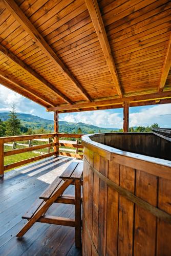a wooden deck with a hot tub and a bench at Casa din Munți Vlădeasa in Rogojel