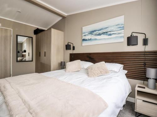 een slaapkamer met een groot wit bed met een houten hoofdeinde bij 63 The Maples in St Austell