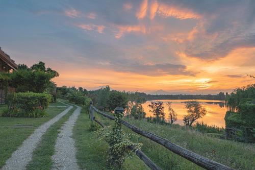 a fence next to a river with a sunset at Le Ali Del Frassino in Peschiera del Garda