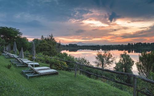 a row of lounge chairs with umbrellas on a lake at Le Ali Del Frassino in Peschiera del Garda