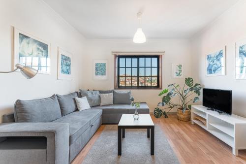 a living room with a gray couch and a tv at Dream Views of Porto - Private Apt in Gaia by Lisbeyond in Vila Nova de Gaia
