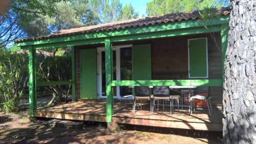 a green cabin with a table and chairs on a deck at Relais du Salagou - Chalets climatisés proche Lac du Salagou in Le Bosc